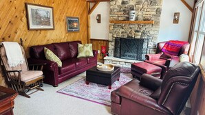 Un salon chaleureux avec une cheminée en pierre, des murs en bois et des meubles en cuir.