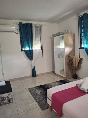 A bedroom with a bed, a wardrobe, a window with curtains, and a small plant.
