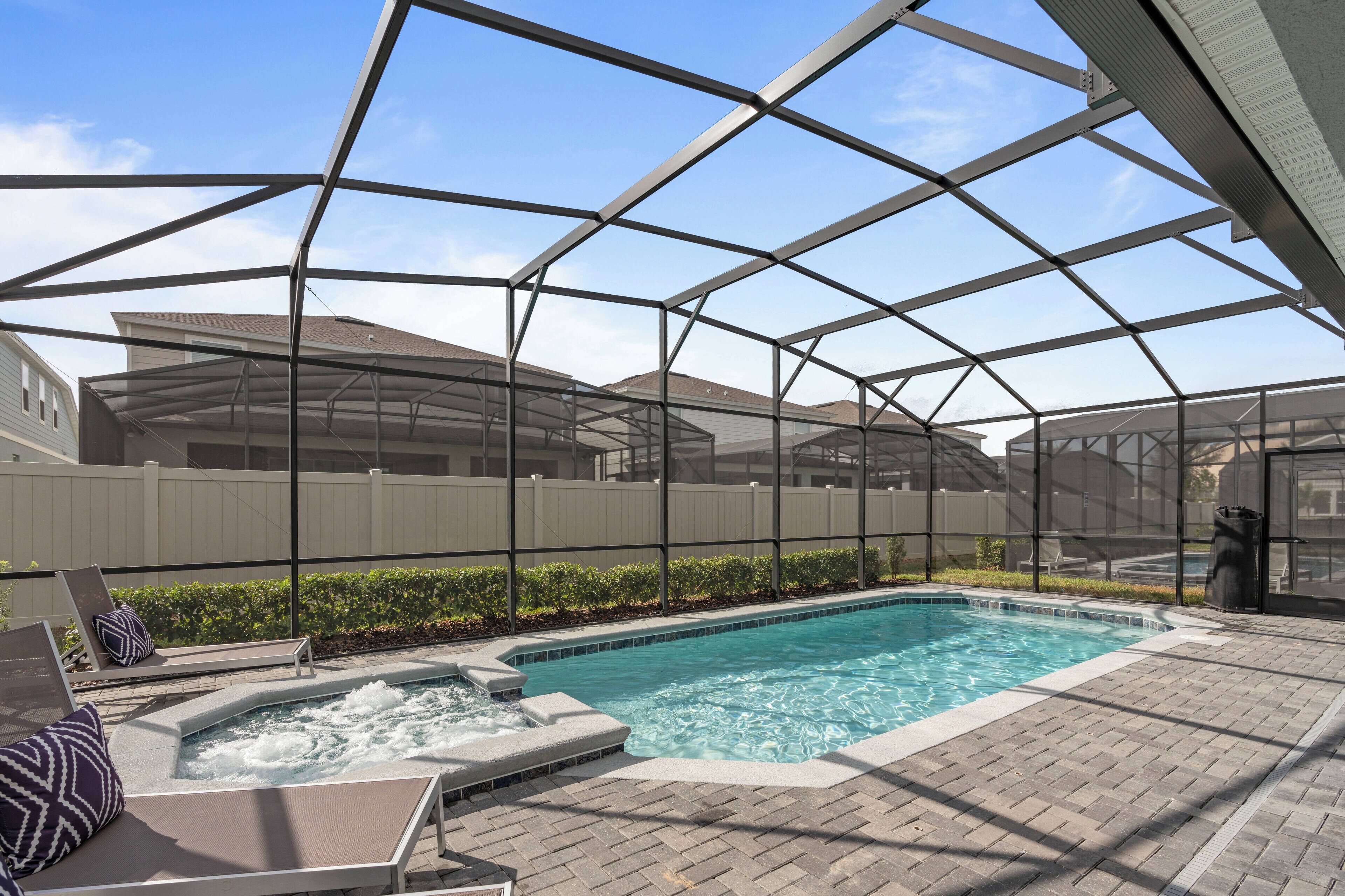 A swimming pool with a hot tub, surrounded by lounge chairs and a covered patio area.