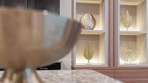 A modern interior with a marble countertop and a decorative bowl in the foreground. Shelves in the background display various leaf-shaped ornaments. - 8BR house sleeps 16 with private pool (Davenport)