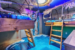 Una habitación con literas, una escalera y un tragaluz circular.