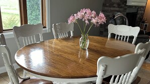 Een ronde houten eettafel omringd door witte stoelen met gesneden rugleuningen.