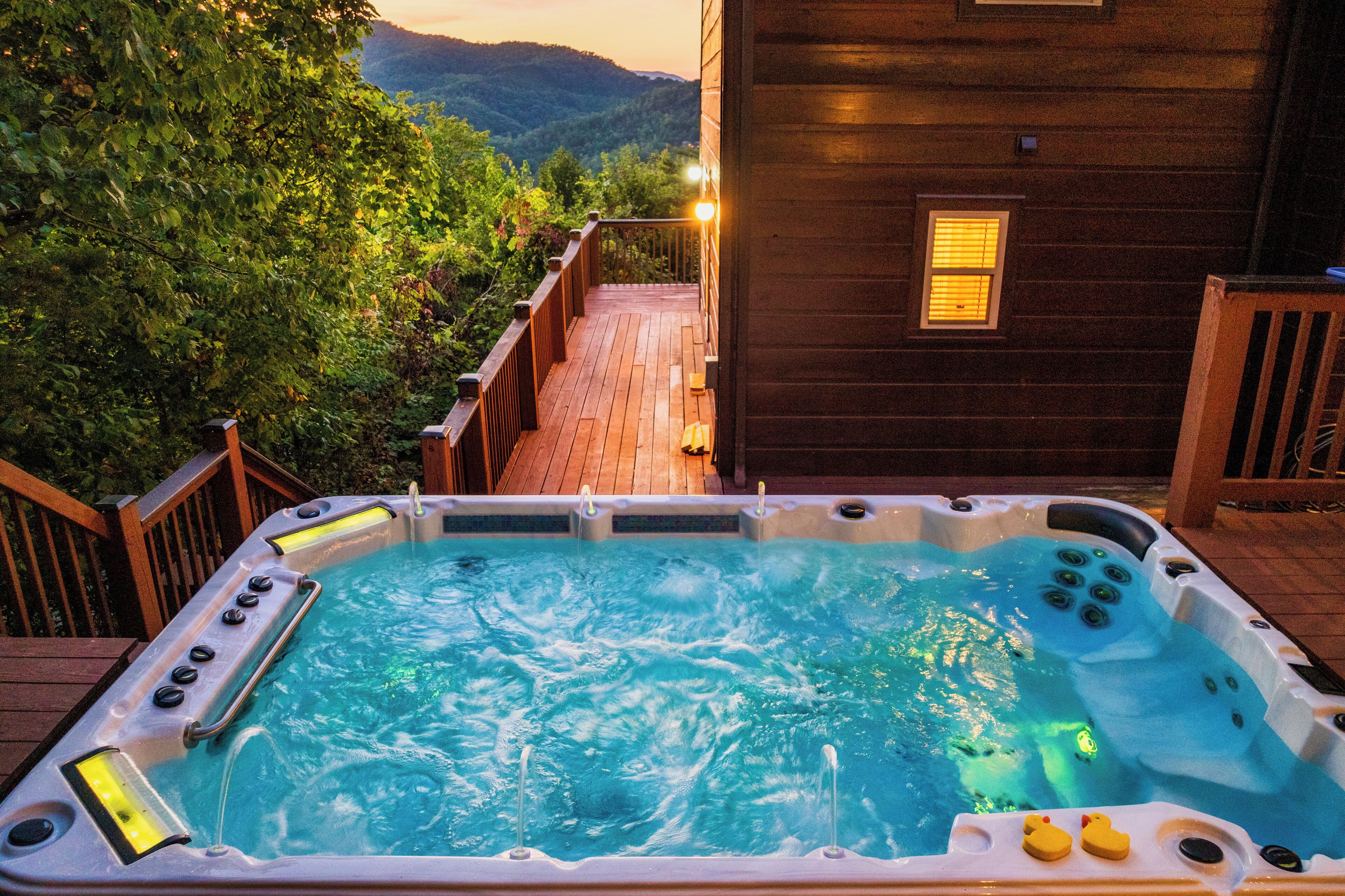 A hot tub with a wooden deck and a mountain view.
