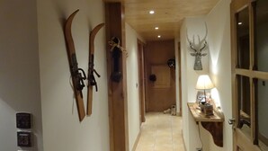 A hallway with wooden walls, a mounted deer head, and skis leaning against the wall.