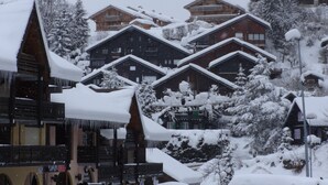 A snow-covered lodge with multiple wooden buildings, a balcony, and a sign indicating a center test.