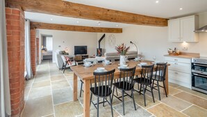 A spacious kitchen with a wooden table set for dining, a fireplace, and a modern TV. - The Granary - UK46002 (Cranswick, near Driffield)