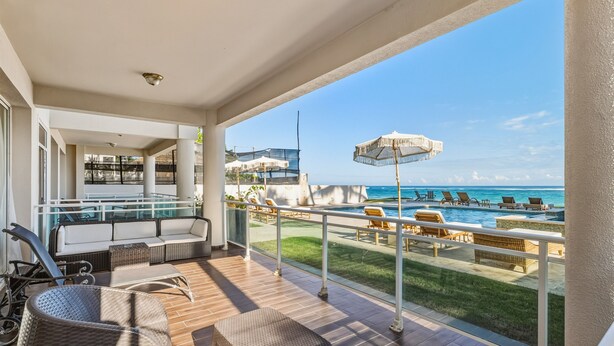 A balcony with a pool, lounge chairs, and a view of the ocean. - Ocean Front Hot tub Pool Kite Beach Condo 101 (Kite Beach)