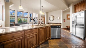 A spacious kitchen with a large island, stainless steel appliances, and a view of the outdoors.