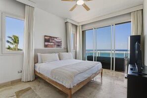 Un dormitorio con cama, televisión y vistas al océano.
