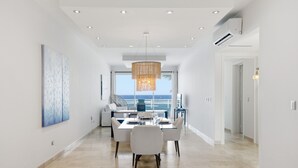 En modern inredning med ett matområde, ett stort fönster med utsikt över havet och en hängande lampa.