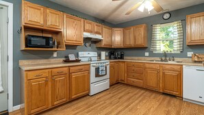 A kitchen with wooden cabinets, a microwave, stove, and a sink.