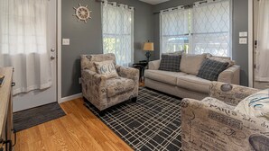 A living room with a patterned armchair, a sofa, and a rug with a geometric design.