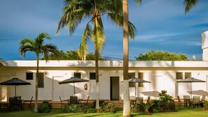 A building with multiple rooms, outdoor seating areas with umbrellas, and palm trees. - Bungalows Casablanca Alamar (Manzanillo)