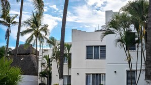 A modern building with a flat roof, surrounded by palm trees and a well-maintained lawn. - Bungalows Casablanca Alamar (Manzanillo)