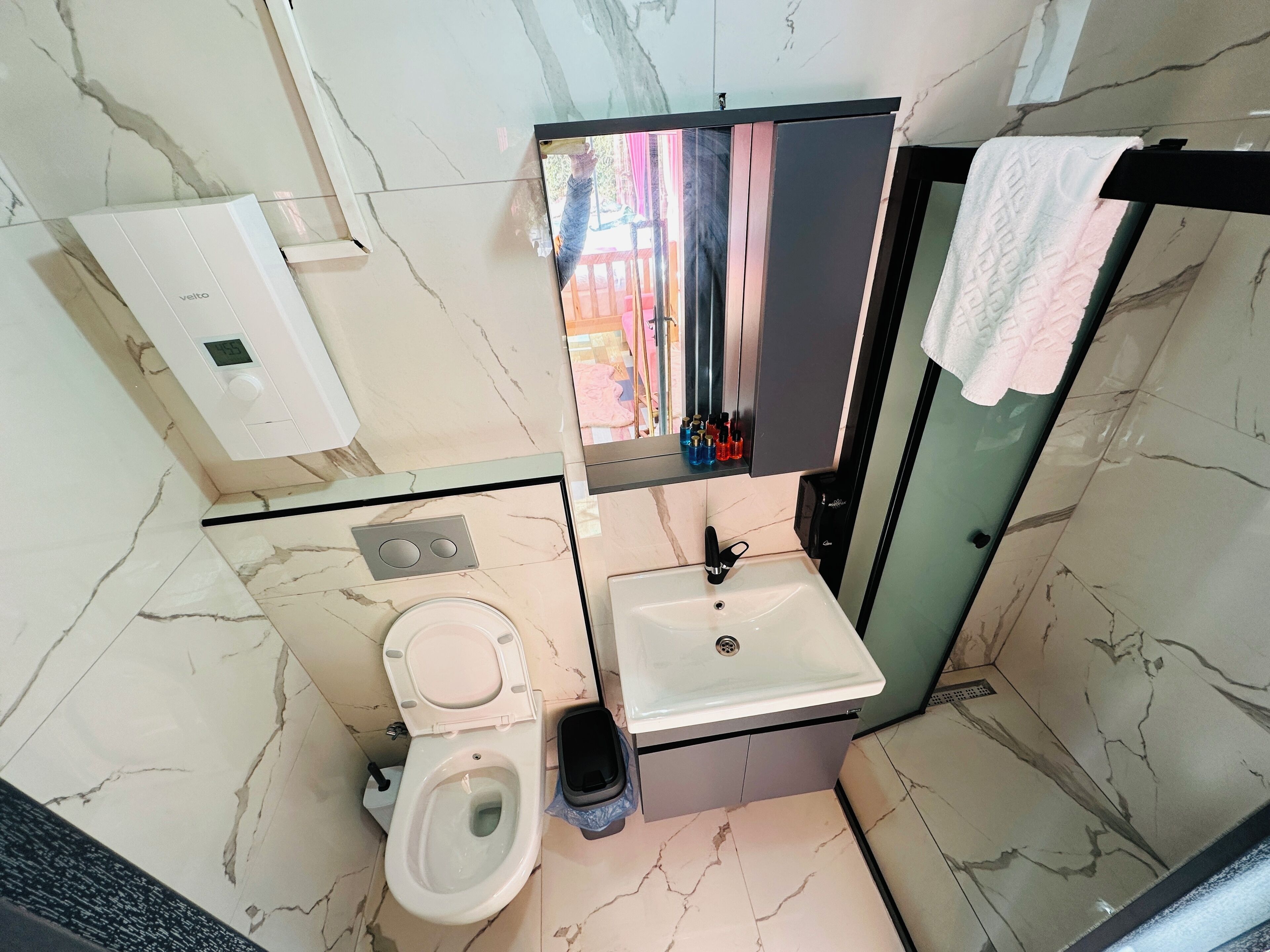 Een kleine badkamer met toilet, wastafel en een spiegel boven de wastafel.