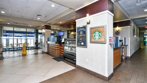 Interior de una cafetería Starbucks con mostrador, zona de mesas y amplias ventanas.