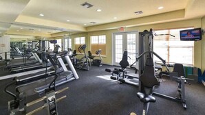 Un gimnasio con cintas de correr, elípticas y equipo de pesas.