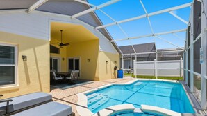 A swimming pool with a hot tub, outdoor seating, and a covered patio area.