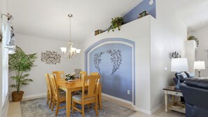 A dining area with a wooden table and chairs, a chandelier, and decorative wall art.