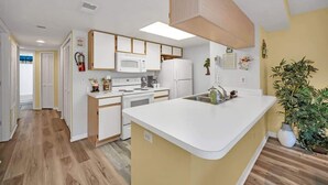 Une cuisine moderne avec des meubles blancs, un îlot central et un four à micro-ondes.