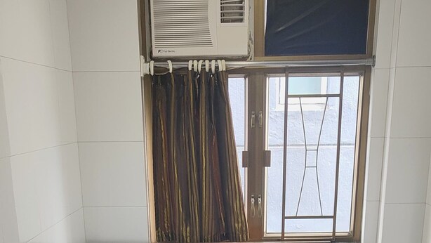 A single bed with a headboard, a window with curtains, a radiator, and a small bedside table with a lamp. - NEW MANDARIN GUEST HOUSE (Kowloon)