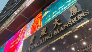A building with a sign for 'CHUNGKING MANSIONS' and a colorful advertisement for 'The New Year with Good Fortune'. - NEW MANDARIN GUEST HOUSE (Kowloon)