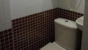 A small bathroom with a toilet, a green grab bar, and a water heater. - NEW MANDARIN GUEST HOUSE (Kowloon)