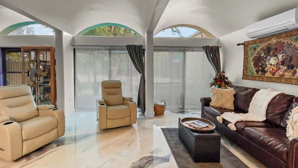 Una sala de estar amplia con un sofá de cuero color beige, un sillón reclinable y una mesita de centro.