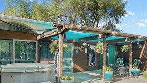 Un patio techado con jacuzzi, mobiliario exterior y plantas en macetas.