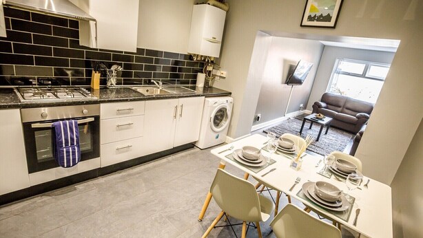 Une cuisine moderne avec un coin repas, un lave-linge et un salon comprenant un canapé et une table basse.