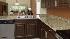 A modern kitchen with dark wood cabinets, granite countertops, and stainless steel appliances. - Luxury Resort Minutes from Disney  (Kissimmee)