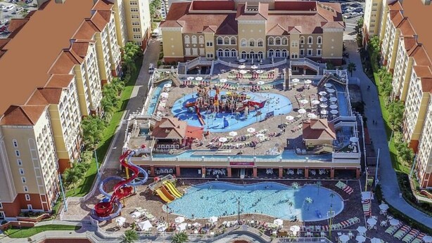 A resort with a central pool, water park, and multiple hotel buildings. - Luxury Resort Minutes from Disney  (Kissimmee)