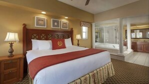 A hotel room with a large bed, a ceiling fan, a bathroom with a bathtub, and a kitchenette. - Luxury Resort Minutes from Disney  (Kissimmee)