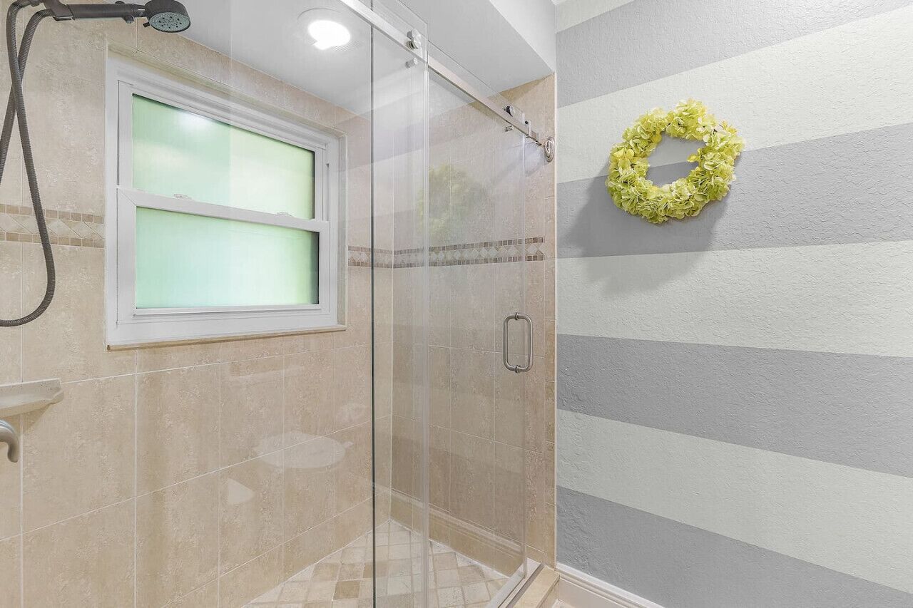 A shower with a frosted glass door, a towel rack, and a towel hanging on the wall.