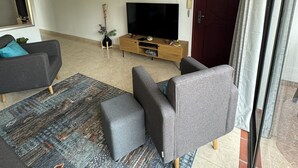 A living room with a flat-screen TV, grey sofas, a wooden TV stand, and a patterned rug. - Beautiful 3-bed 2-bath aptartment on la 70 with Air conditioning (Medellín)