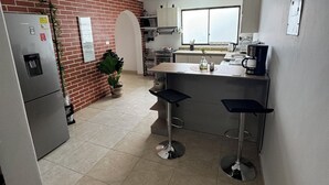 A modern kitchen with a brick accent wall, stainless steel appliances, and a bar area with stools. - Beautiful 3-bed 2-bath aptartment on la 70 with Air conditioning (Medellín)