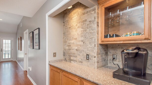 A kitchen with a stone backsplash, wooden cabinets, and a Keurig coffee maker. - Charming 2-bedroom, 2bath home in lovely Hammond (Hammond)