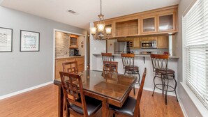 A dining area with a glass-top table, wooden chairs, and a chandelier. - Charming 2-bedroom, 2bath home in lovely Hammond (Hammond)