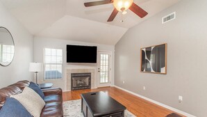 A living room with a brown leather couch, a coffee table, a fireplace, and a ceiling fan. - Charming 2-bedroom, 2bath home in lovely Hammond (Hammond)