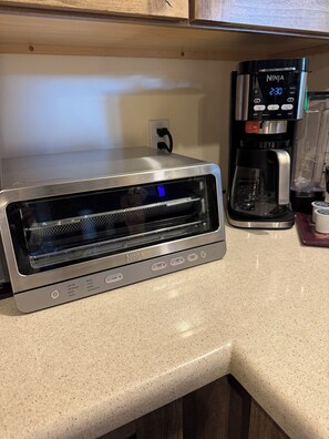 Een keuken met een toaster, een koffiezetapparaat en een blender op het aanrecht.