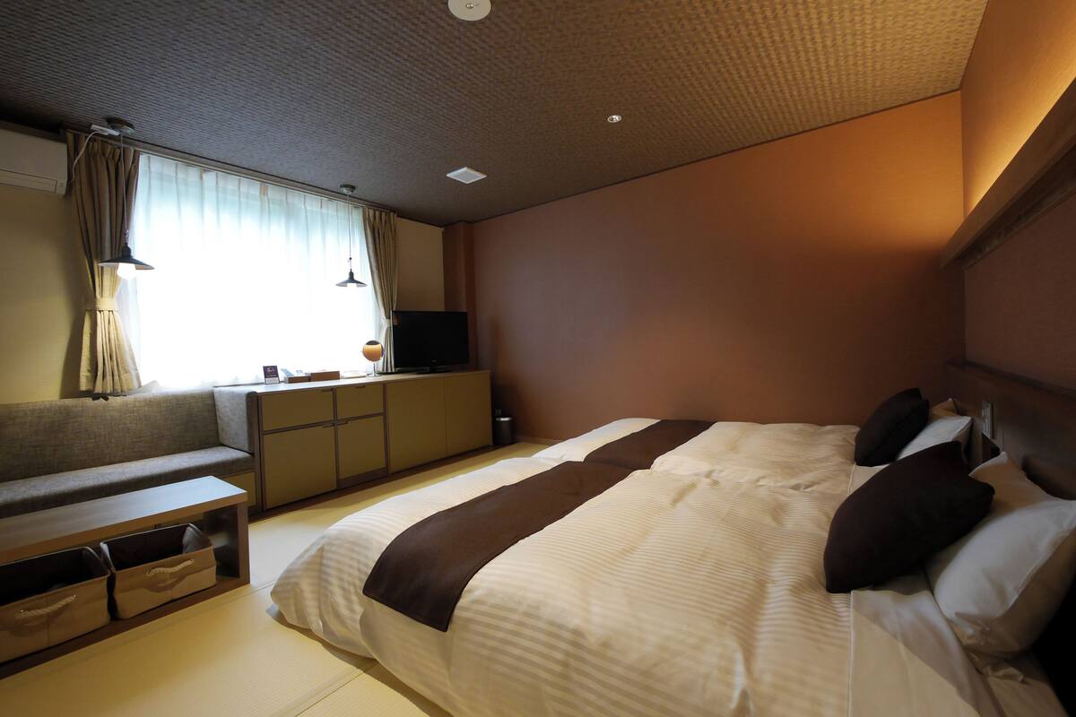 Een hotelkamer met een bed, een bank, een bureau en een raam met gordijnen.