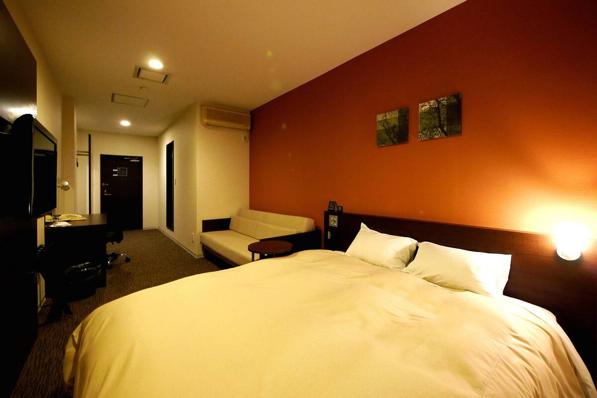 Een hotelkamer met een groot bed, een slaapbank, een bureau met telefoon en een televisie.