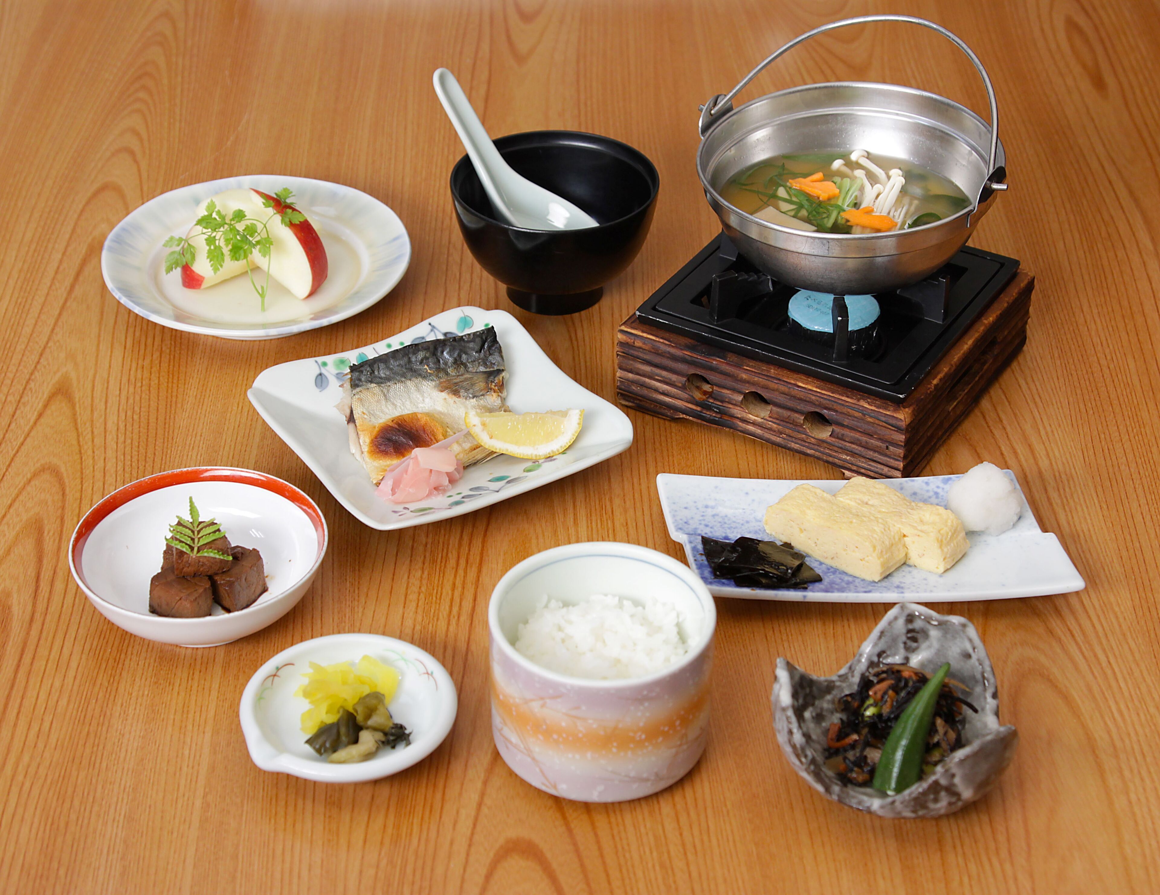 Diversos pratos, incluindo peixe, tofu e vegetais em conserva, sobre uma mesa de madeira.