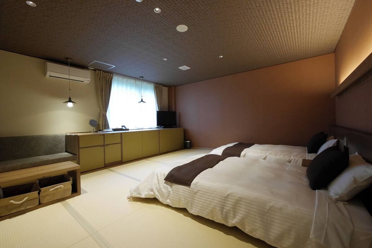 Een slaapkamer met een bed, een slaapbank, een nachtkastje en een airconditioning.