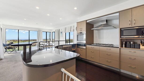 Una cocina moderna con una isla central, electrodomésticos de acero inoxidable y vistas al exterior.