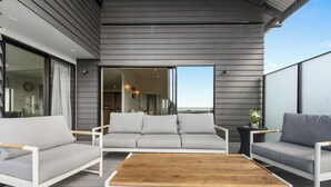 Un área de estar exterior moderna con una mesa de centro de madera, dos sofás y una mesita auxiliar.