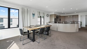 Una cocina moderna con una isla central, una zona de comedor con una mesa de madera y cuatro sillas, y un ventanal con cortinas.