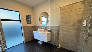 A modern bathroom with a glass-enclosed shower, a white vanity with a round mirror, and a motivational quote on the wall. - Pedal and Play - Cromwell Holiday Home (Cromwell)