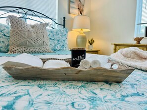 Un dormitorio acogedor con una cama, una bandeja con una taza, toallas y un libro.