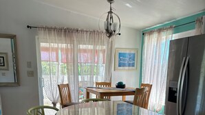 Una cocina con isla central, sillas, refrigerador y mesa de comedor.